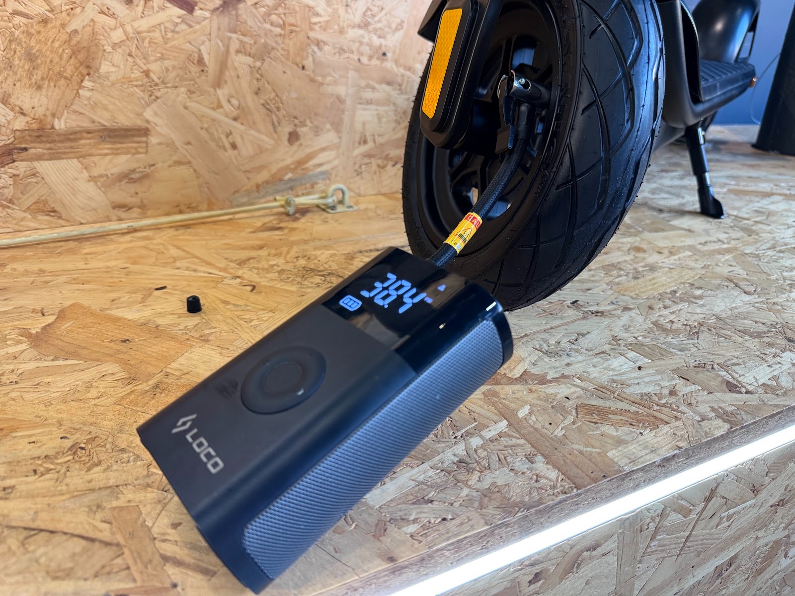 Checking tire pressure on an electric scooter wheel with a LOCO portable compressor.
